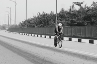 Schwarz-Weiß-Foto eines Rennradfahrers auf einer Straße