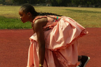 Eine schwarze Person auf Startposition auf einer Laufstrecke.