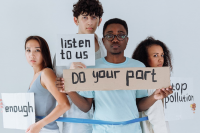 Vertreter:innen der Gen Z mit Demo-Schildern in der Hand auf denen stehen: enough; listen to us; do your part; stop pollution